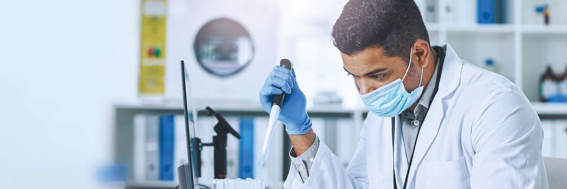 Enzymes, NGS, Black male pipetting in front of computer screen in a laboratory environment